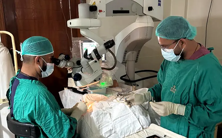 Surgeons operating with a microscope in a partner hospital theatre